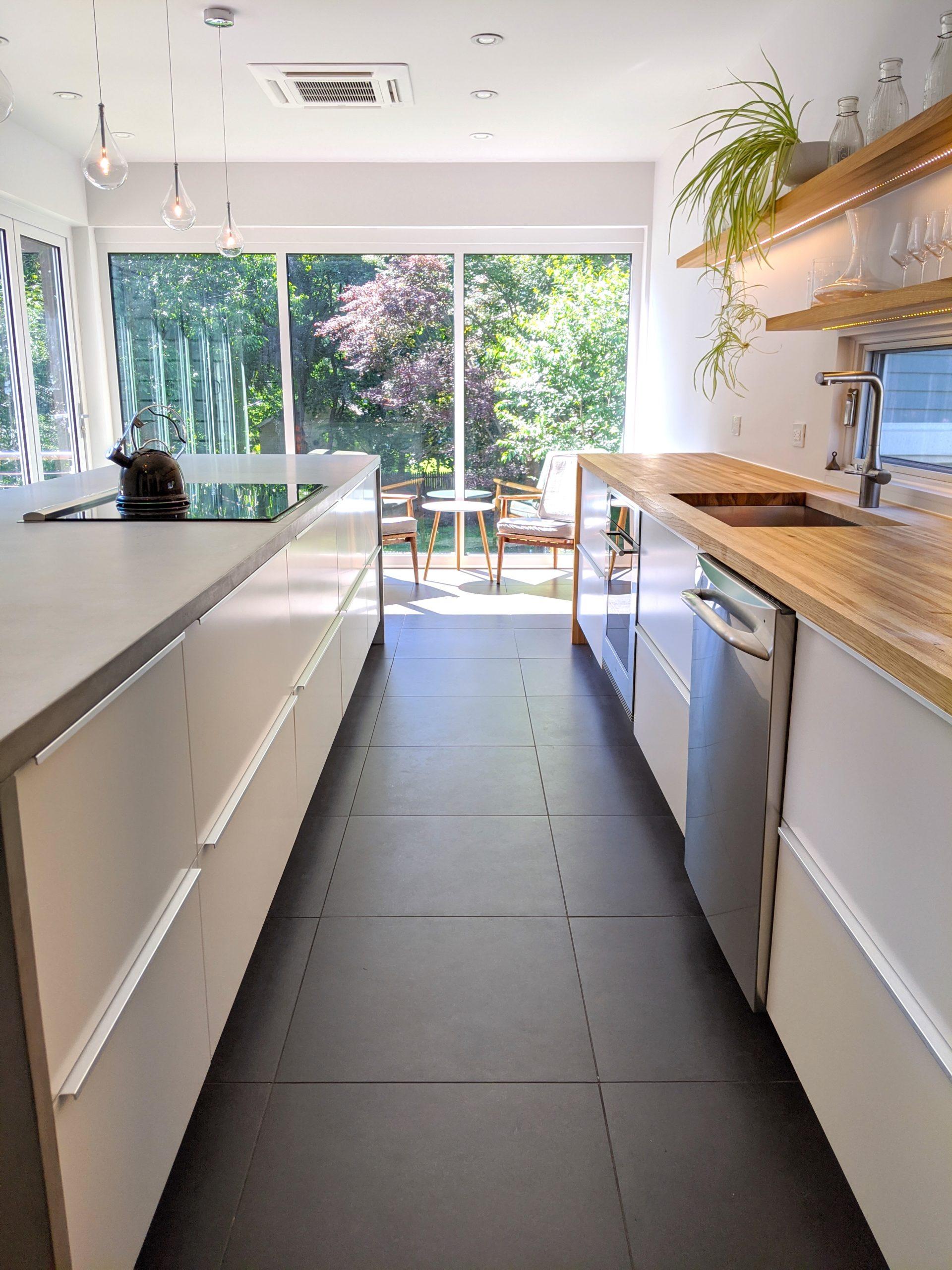 Biophilic kitchen with black floor white cabinets and concrete counter island