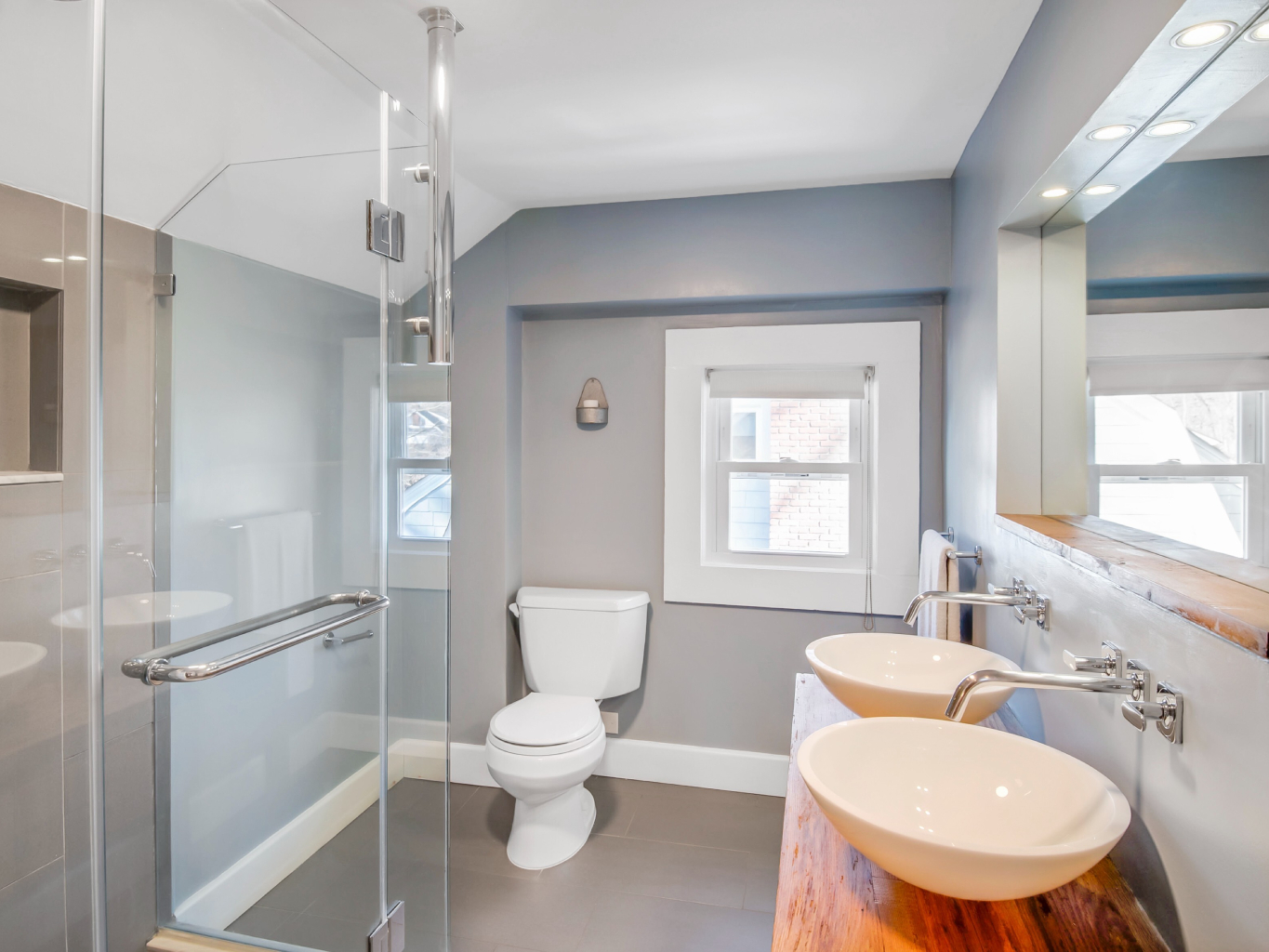 Gray bathroom with hickory butcher block vanity and double vessel sinks