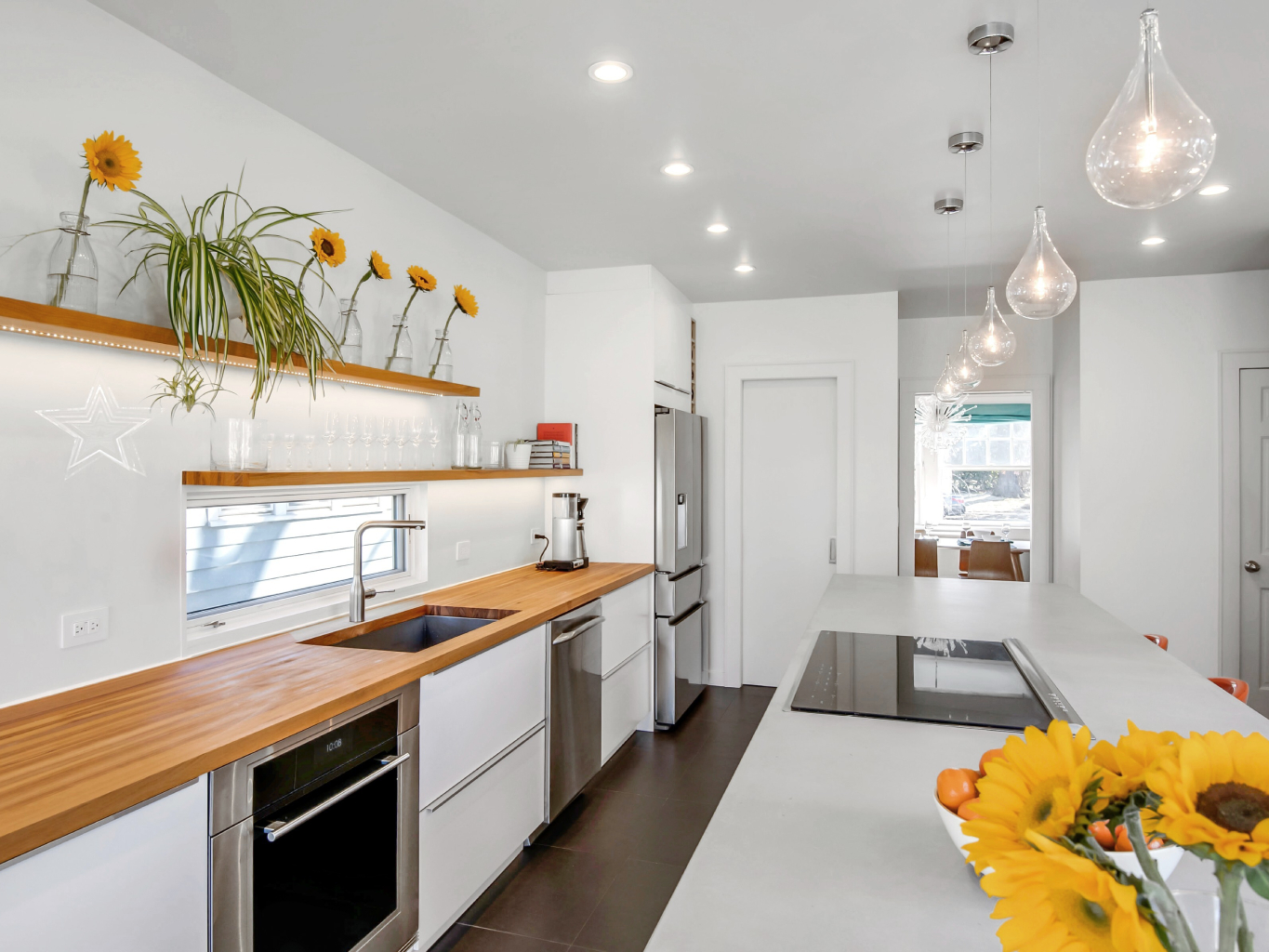 Bright and open floor plan white kitchen with floating wood shelves